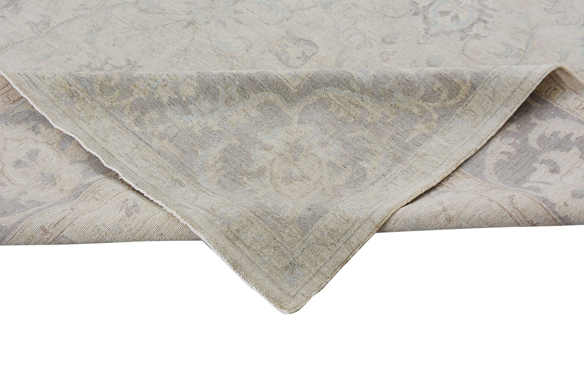 A corner of a handmade Afghan Chobi rug with a light beige and grey traditional floral pattern.