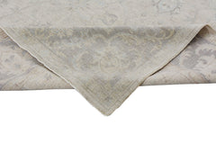 A corner of a handmade Afghan Chobi rug with a light beige and grey traditional floral pattern.