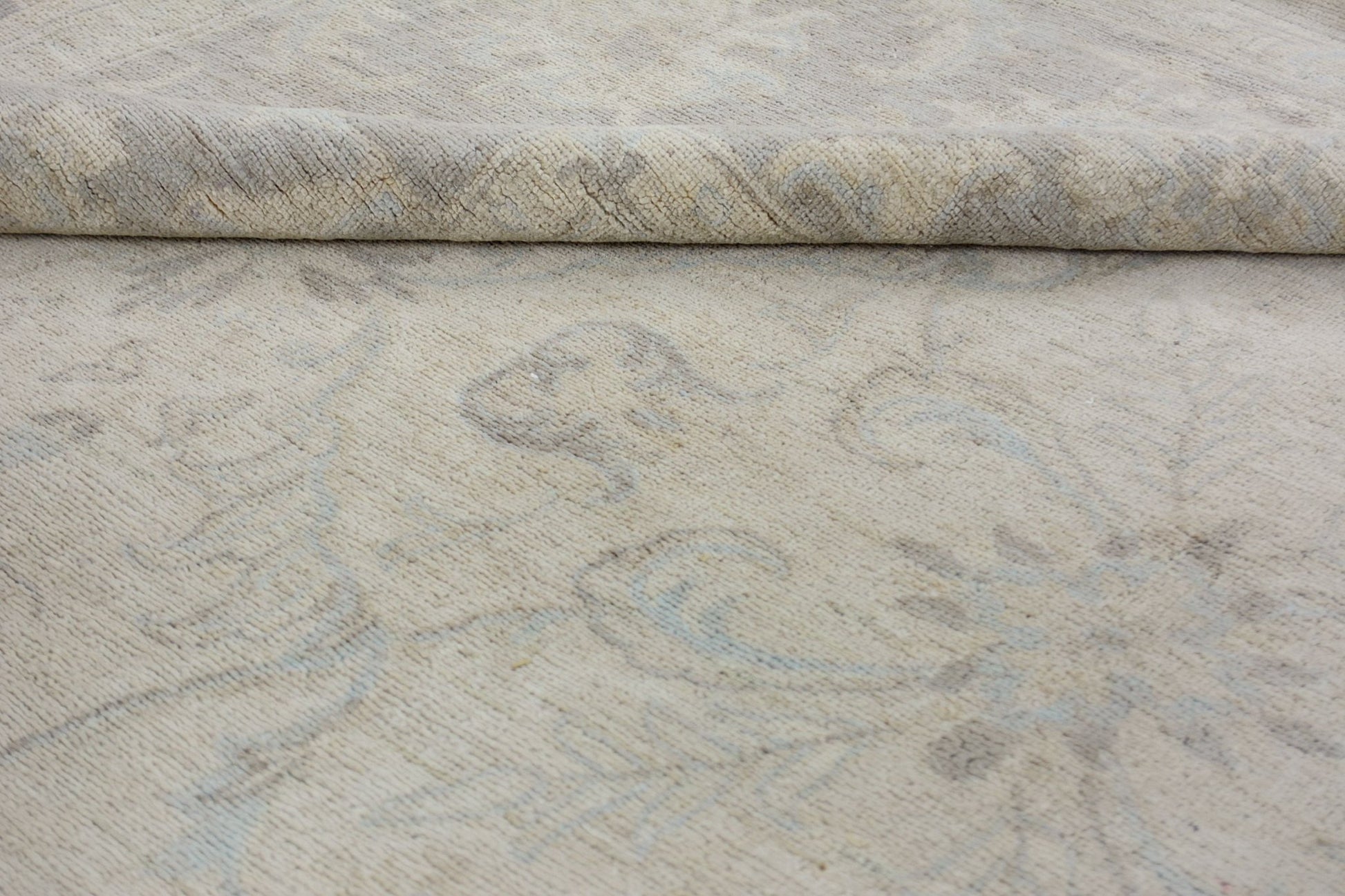 A close-up of a handmade Afghan Chobi rug featuring a subtle, light-toned floral pattern.
