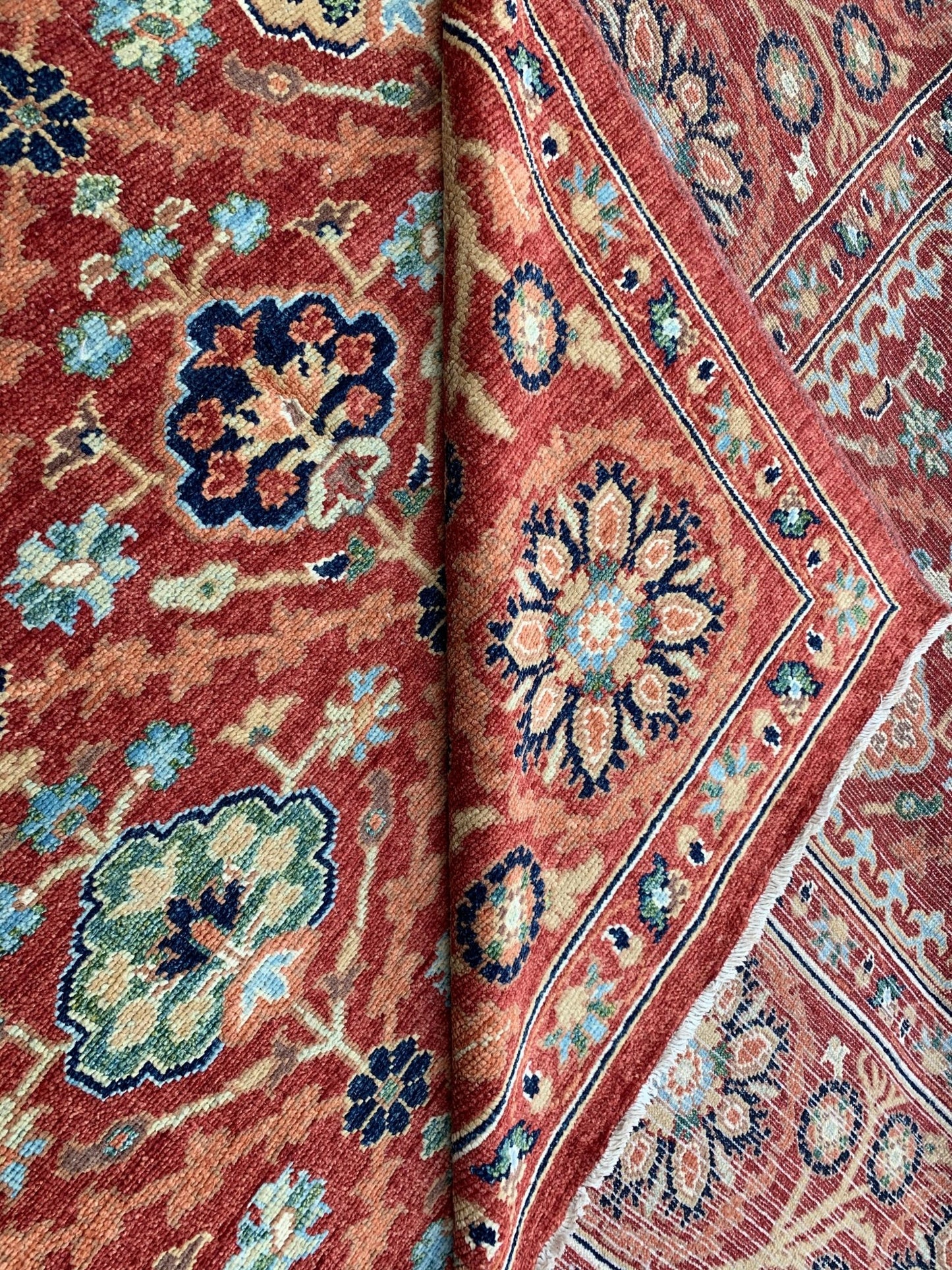 A handmade Afghan Chobi rug featuring a traditional floral pattern in shades of red and blue.