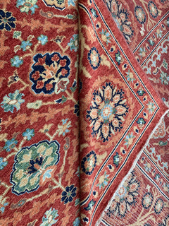 A handmade Afghan Chobi rug featuring a traditional floral pattern in shades of red and blue.