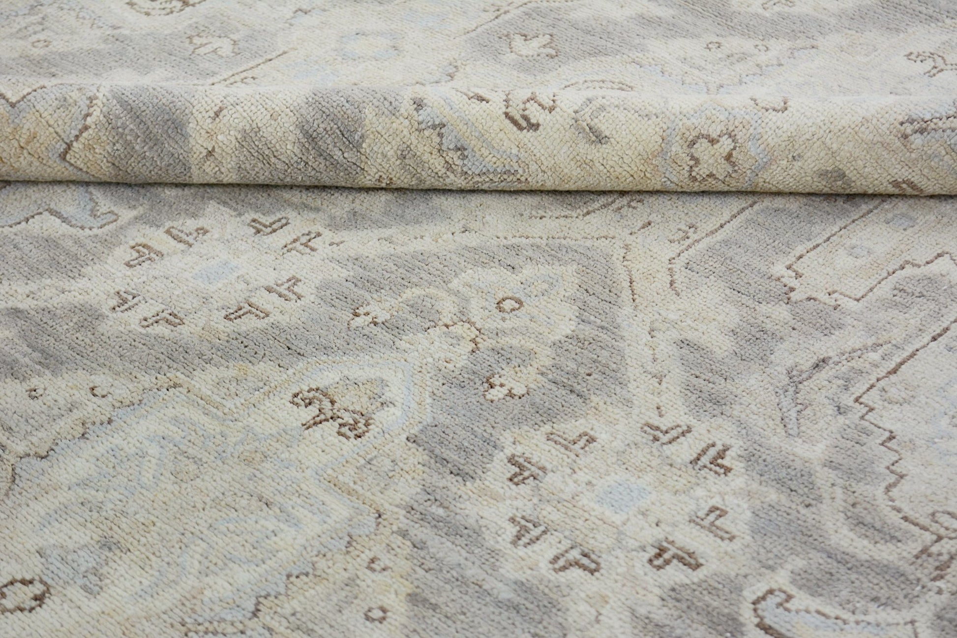 A handmade Afghan Chobi rug featuring a traditional pattern in neutral beige and grey tones.