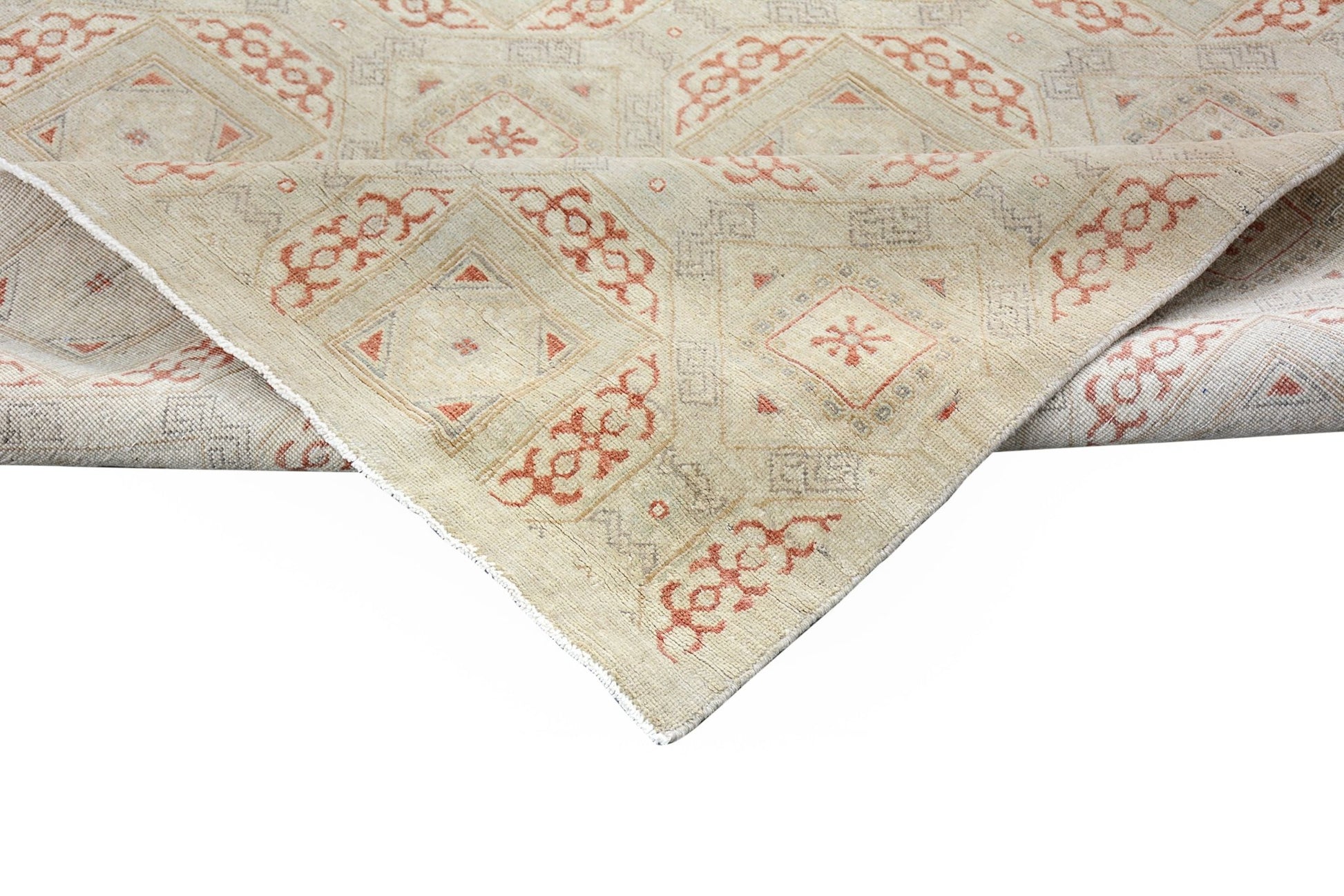 A handmade Afghan Chobi rug featuring a geometric pattern in soft beige and muted orange tones.