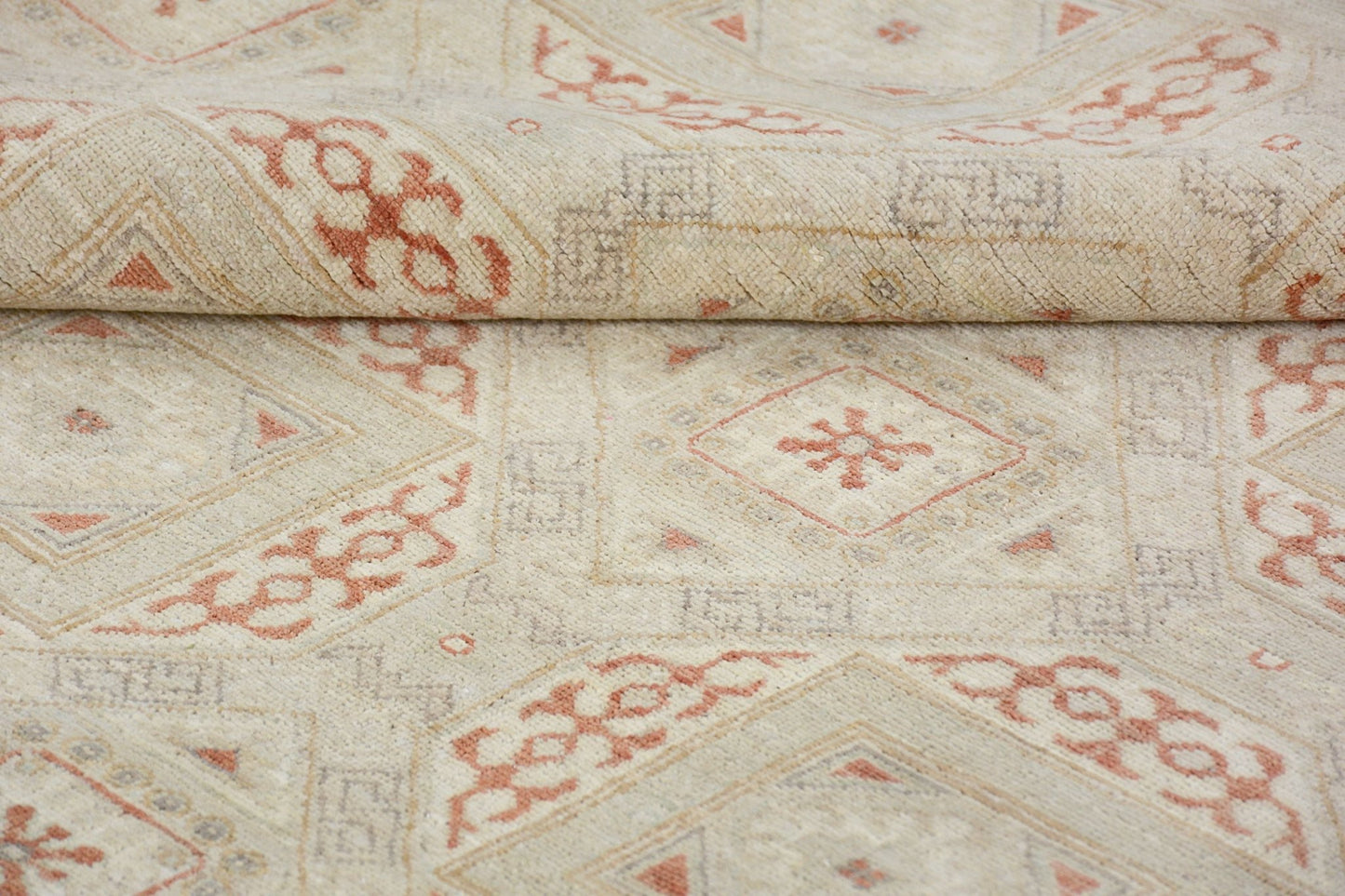 A handmade Afghan Chobi rug featuring a geometric diamond pattern in soft terracotta and cream.