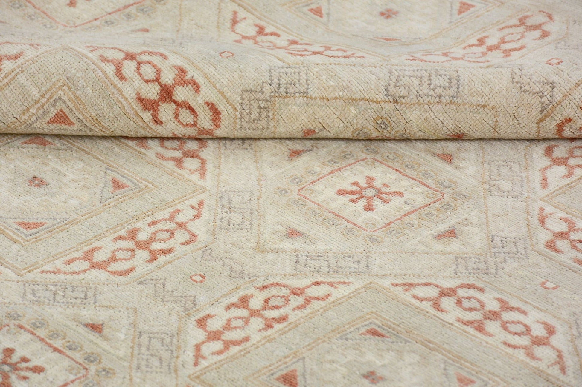 A handmade Afghan Chobi rug featuring a geometric diamond pattern in soft terracotta and cream.