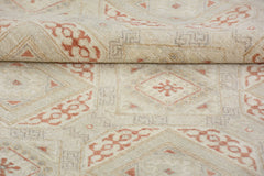 A handmade Afghan Chobi rug featuring a geometric diamond pattern in soft terracotta and cream.