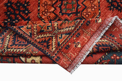 A handmade Afghan Chobi rug featuring traditional geometric patterns in shades of red and blue.