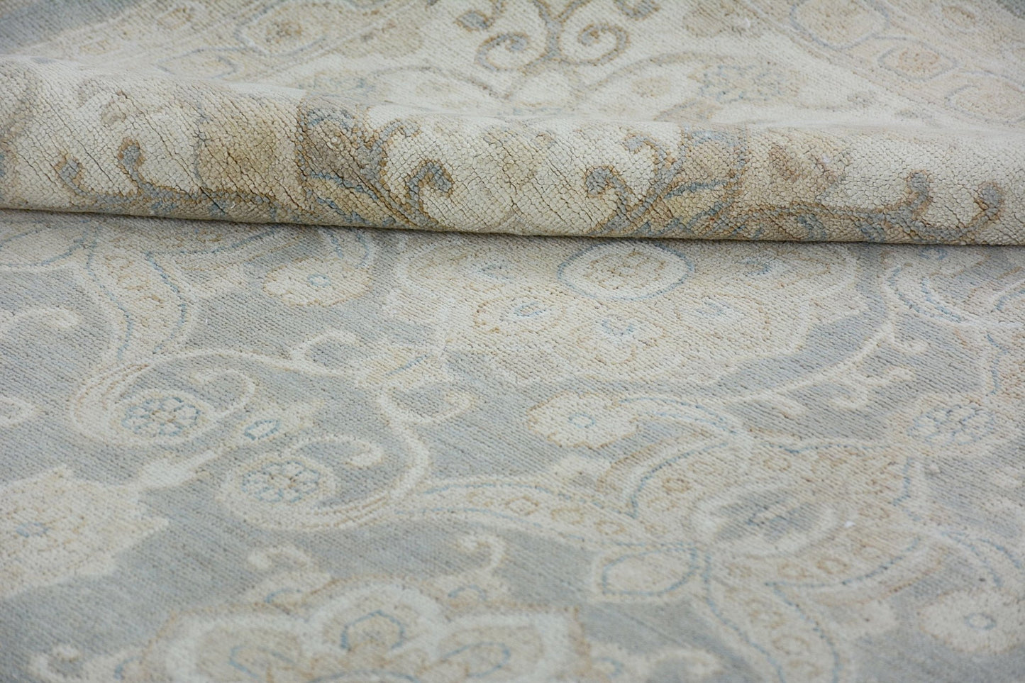 A handmade Afghan Chobi rug featuring a traditional floral pattern in soft beige and blue tones.