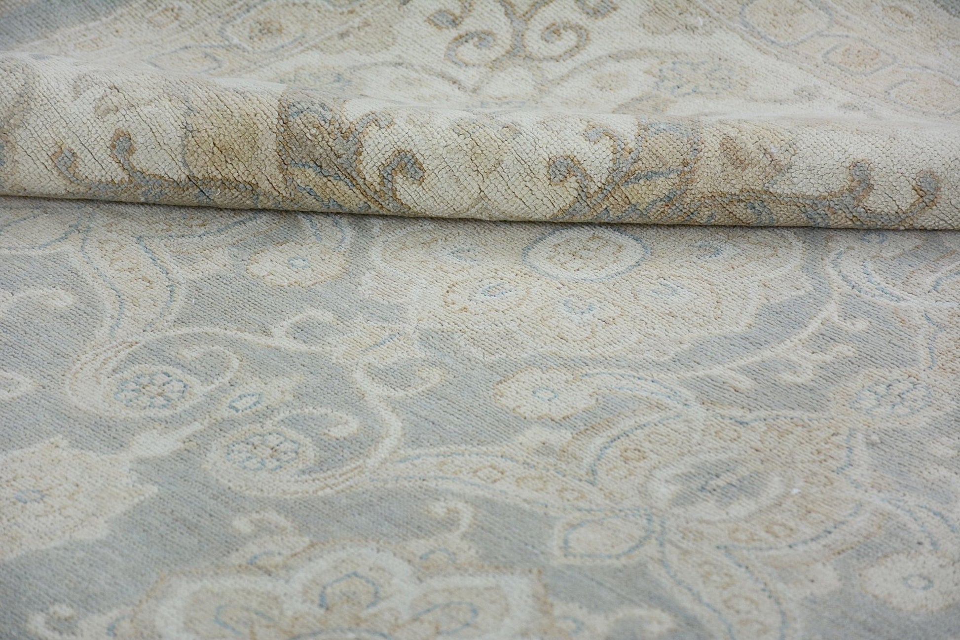 A handmade Afghan Chobi rug featuring a traditional floral pattern in soft beige and blue tones.