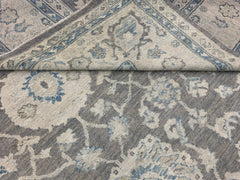 A handmade Afghan Chobi rug featuring a traditional floral pattern in shades of grey and blue.