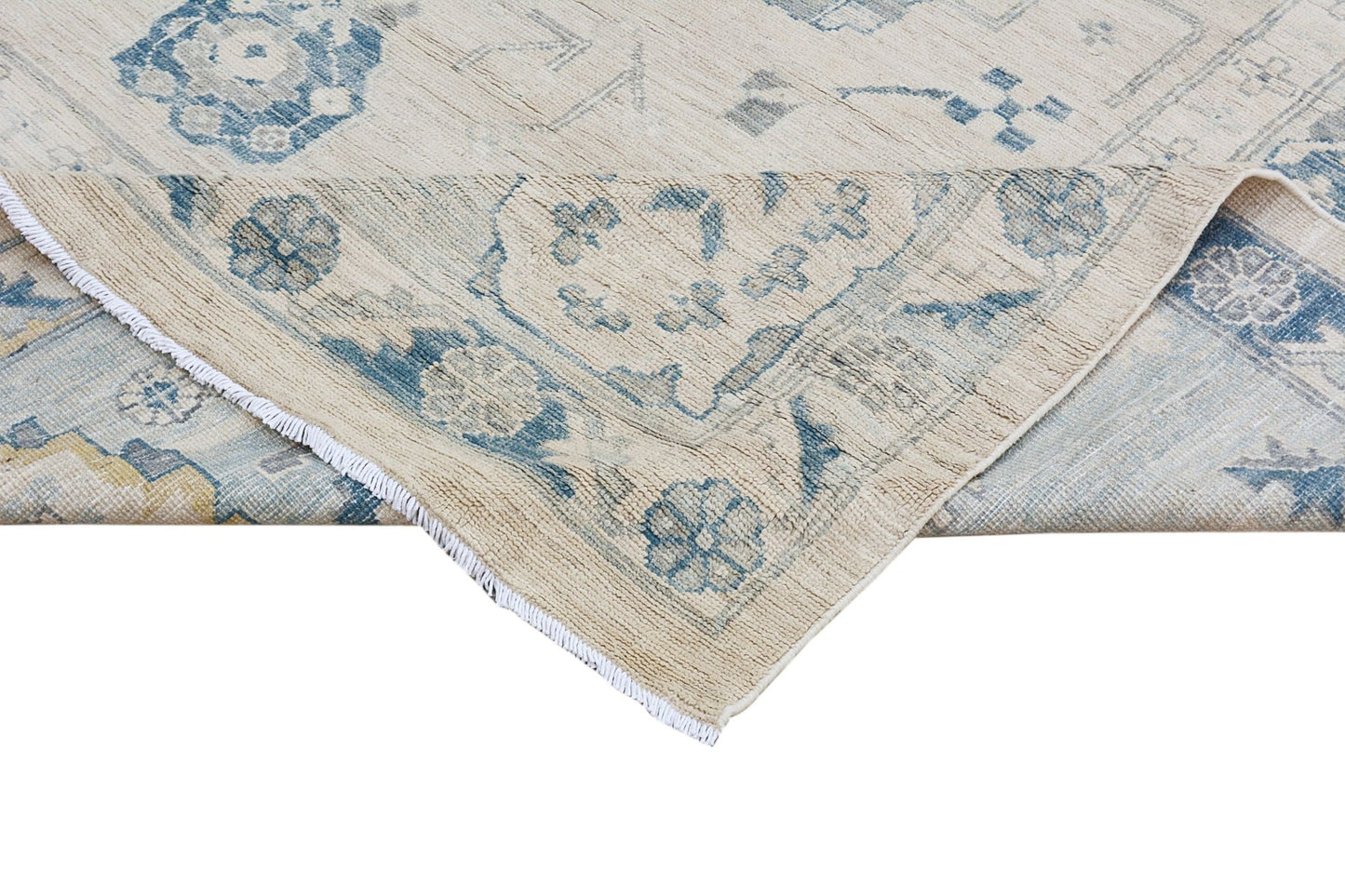 A handmade Afghan Chobi rug featuring a traditional floral pattern in blue on a cream background.