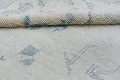 A handmade Afghan Chobi rug featuring a cream wool pile with a soft blue floral pattern.