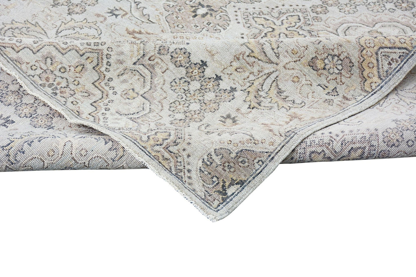 An Afghan Chobi rug with a traditional floral pattern in neutral wood tones and a folded corner.