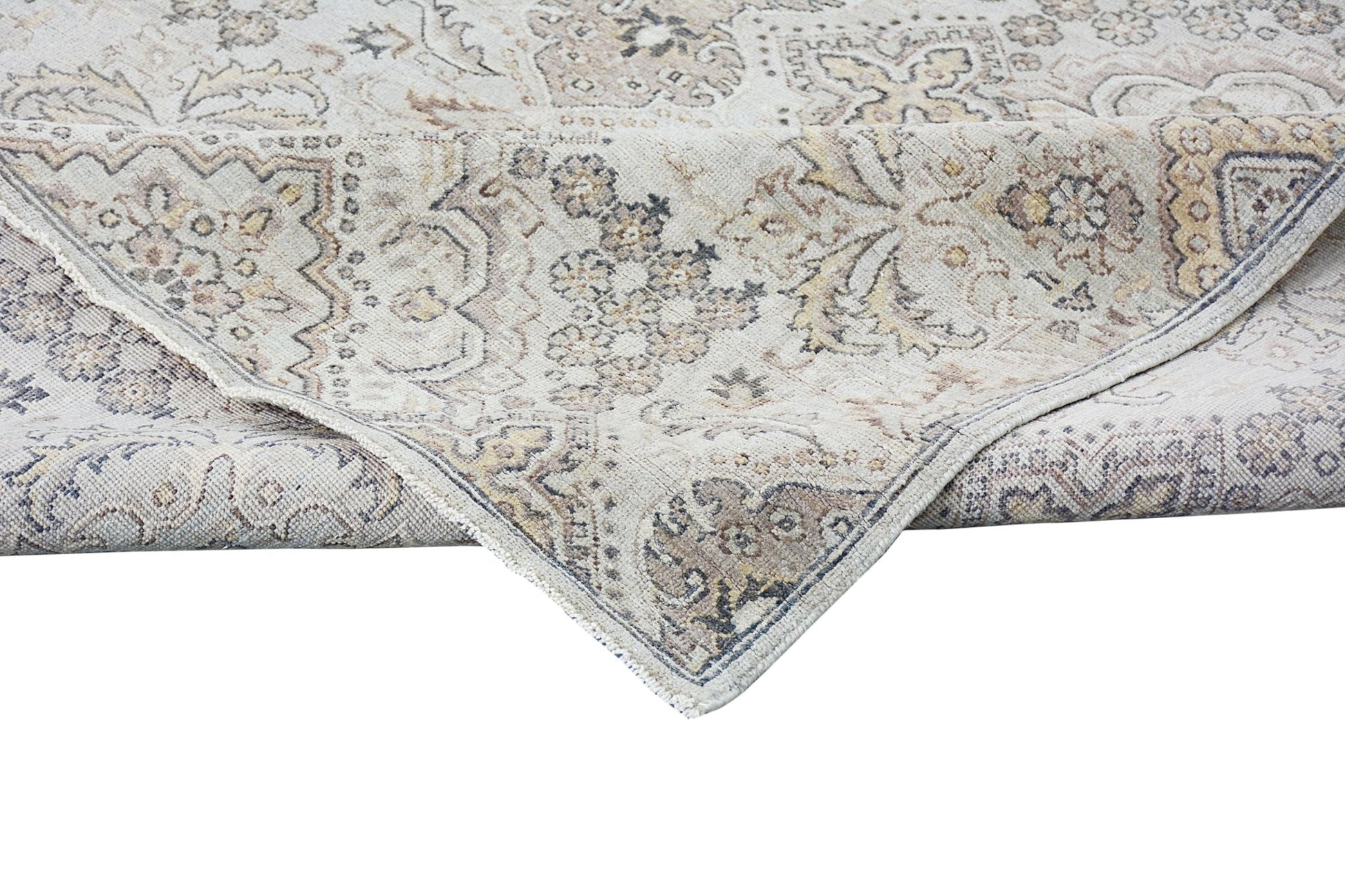 An Afghan Chobi rug with a traditional floral pattern in neutral wood tones and a folded corner.