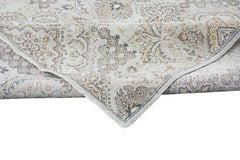 An Afghan Chobi rug with a traditional floral pattern in neutral wood tones and a folded corner.