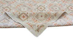 A handmade Afghan Chobi rug featuring a geometric pattern in earthy tones with a folded corner.