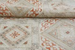 A handmade Afghan Chobi rug featuring a geometric pattern in soft orange and beige tones.