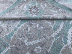 A handmade Afghan Chobi rug featuring a traditional floral pattern in shades of teal and grey.