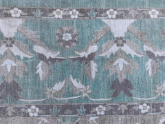 A handmade Afghan Chobi rug featuring a teal field with intricate floral and botanical patterns.