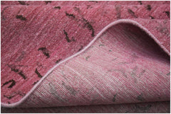 A close-up of a pink overdyed Afghan Chobi rug showing its handwoven wool texture and cotton base.