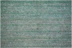 A close-up of a handwoven Afghan Chobi rug featuring a textured, overdyed green wool surface.