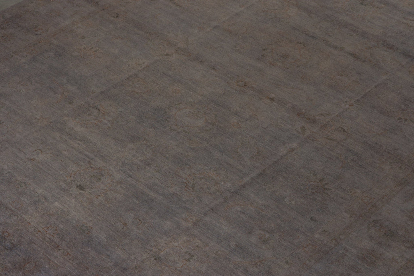 An overdyed Afghan Chobi rug featuring a subtle, muted pattern on a dark grey wool surface.