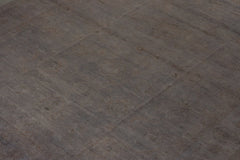 An overdyed Afghan Chobi rug featuring a subtle, muted pattern on a dark grey wool surface.