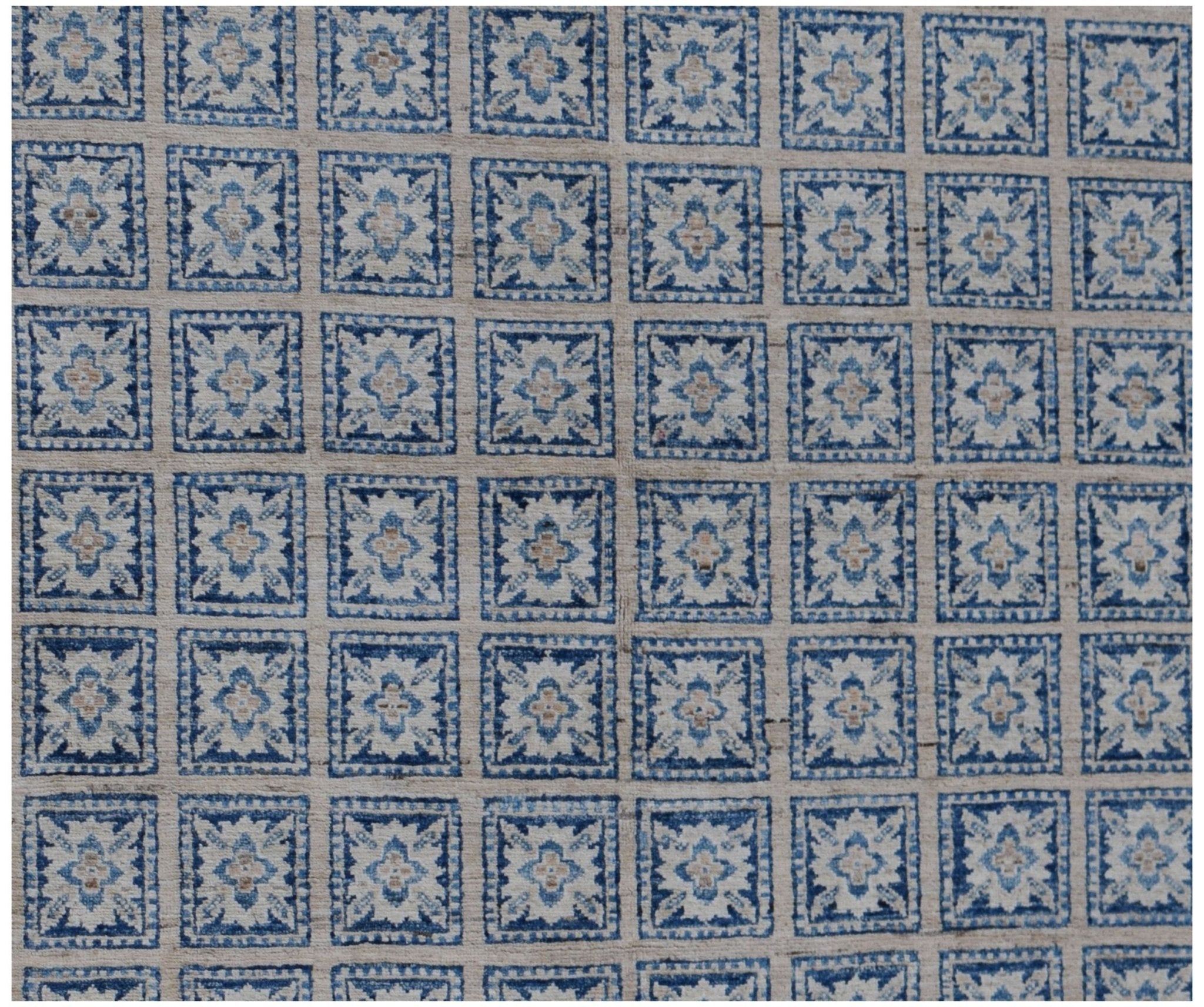 Handmade Afghan Chobi rug featuring a repeating grid of blue and cream floral motifs.
