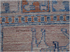 A close-up of a handmade Afghan Chobi rug featuring geometric patterns in blue and orange wool.