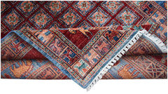 A handwoven Afghan Chobi rug featuring a geometric diamond pattern and a decorative animal border.