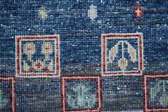 A close-up of a handmade Afghan Chobi rug featuring geometric motifs in red and blue squares.