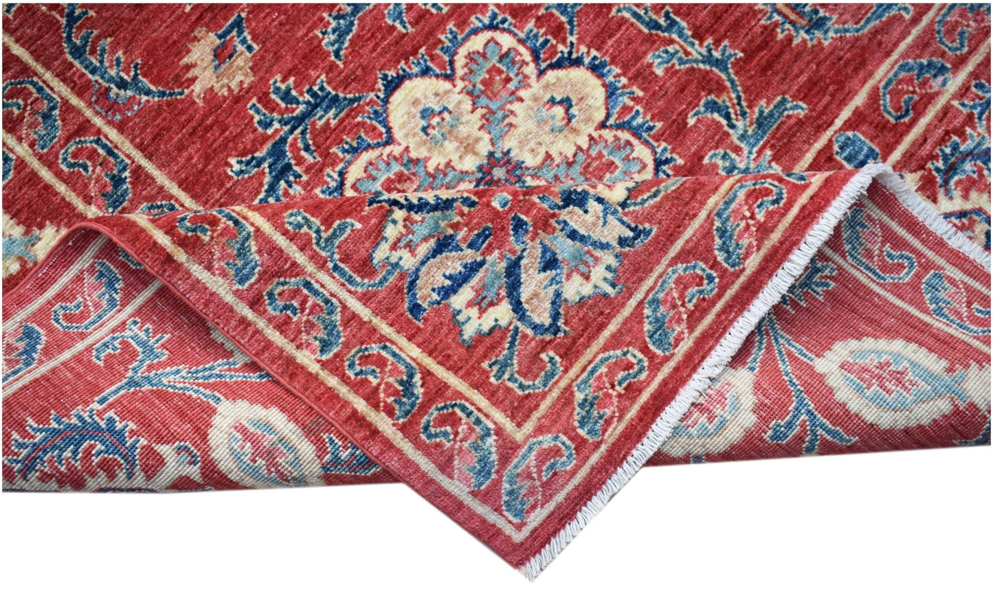 A handmade Afghan Chobi rug featuring a traditional red floral Suzani pattern on a wool pile.