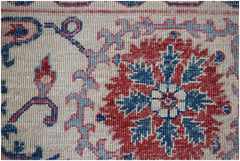 A close-up of an Afghan Chobi rug featuring a red floral medallion on a cream background.