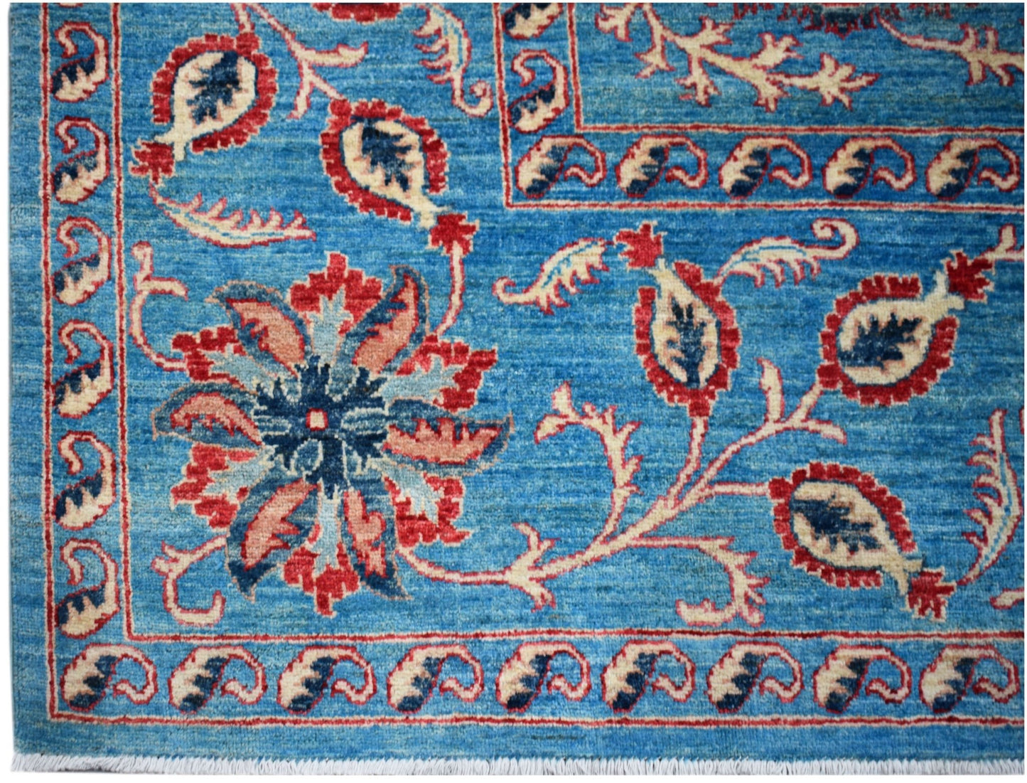 Handwoven Afghan Chobi rug featuring a blue field with traditional red and cream floral motifs.