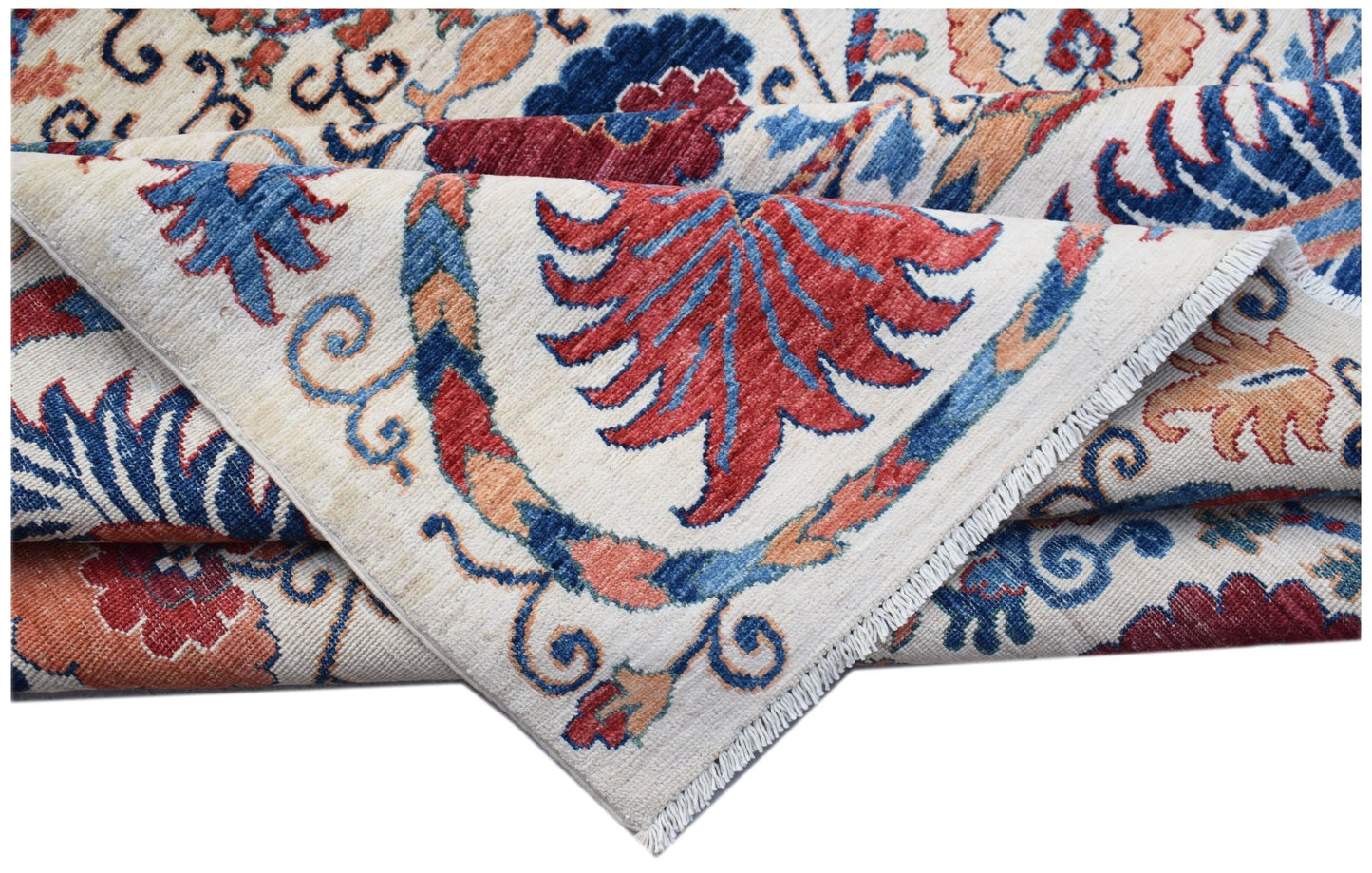 A folded Afghan Chobi rug featuring a traditional floral Suzani pattern in red, blue, and tan.