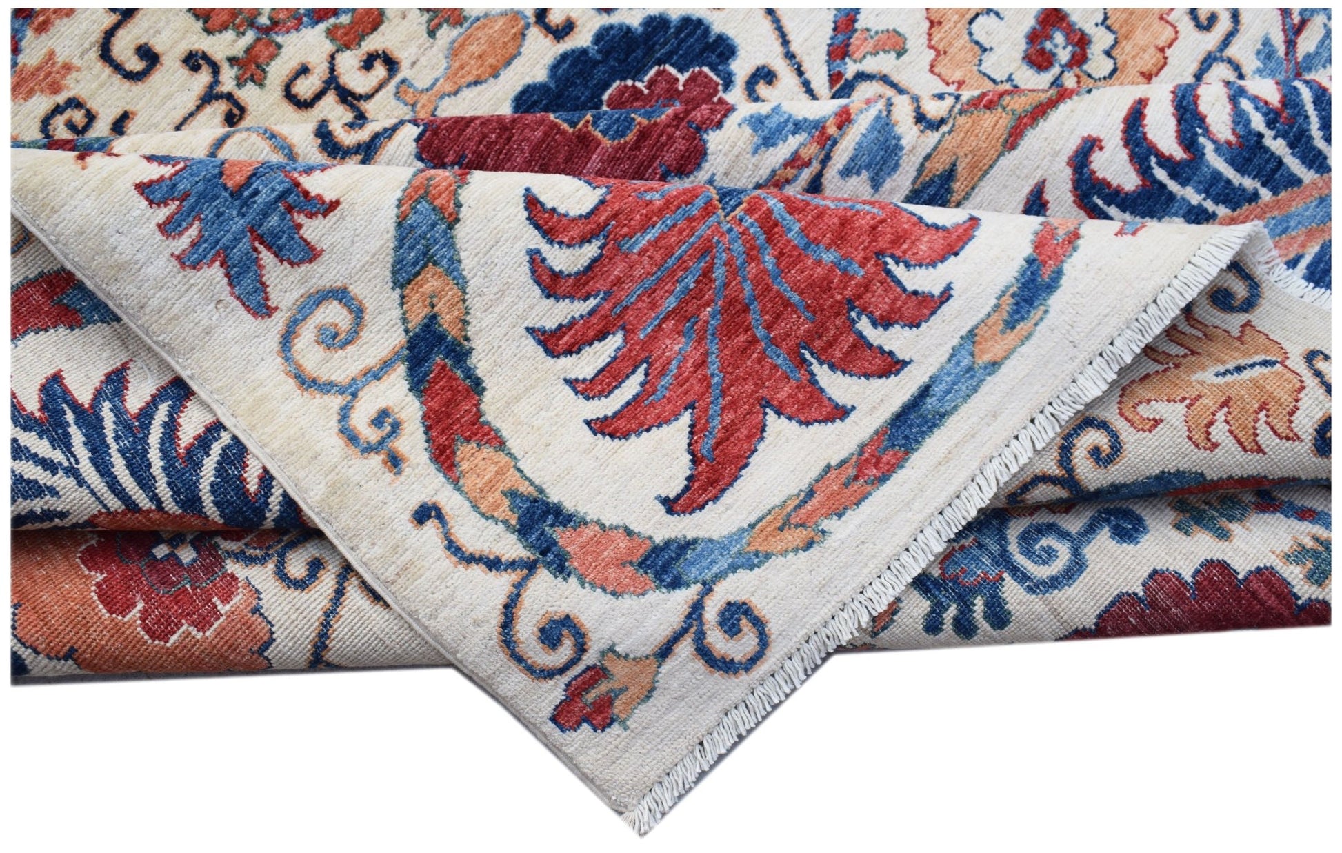 A folded Afghan Chobi rug featuring a traditional floral Suzani pattern in red, blue, and tan.