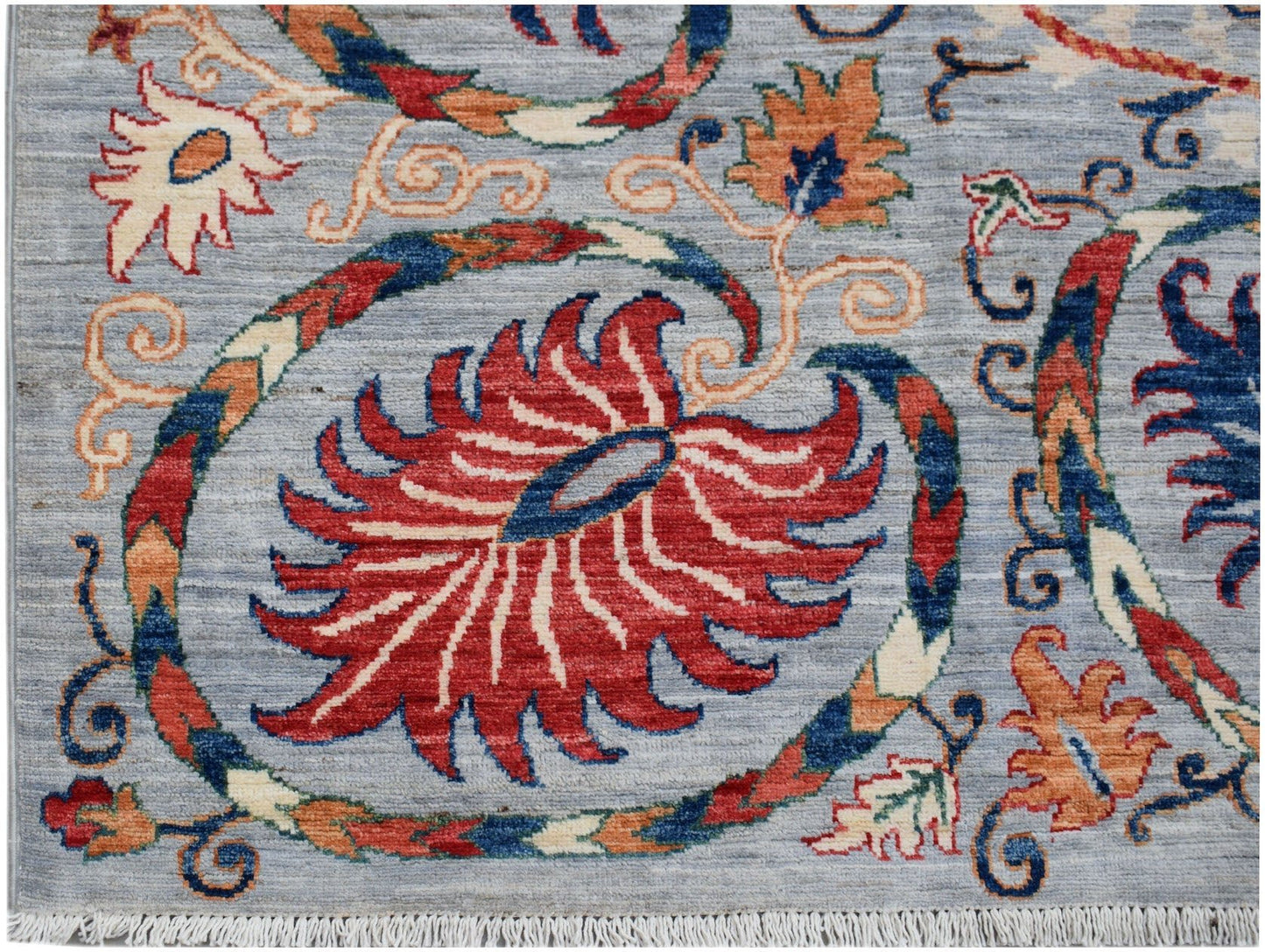 A handmade Afghan Chobi rug featuring a traditional Suzani floral pattern on a light blue background.