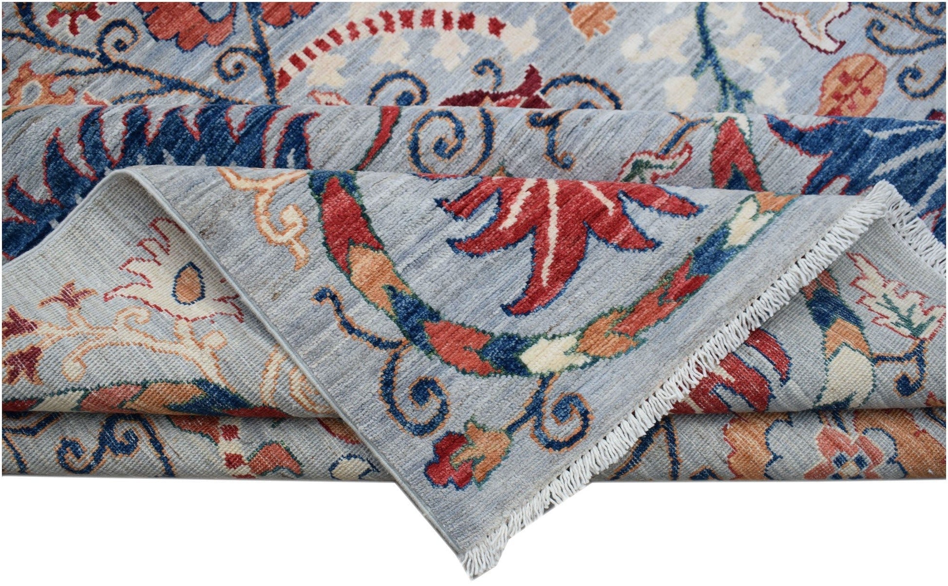 A folded Afghan Chobi rug featuring a light blue background with traditional floral patterns.