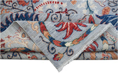 A folded Afghan Chobi rug featuring a light blue background with traditional floral patterns.