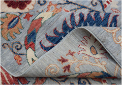 A folded Afghan Chobi rug featuring a traditional Suzani floral pattern in blue, red, and cream.