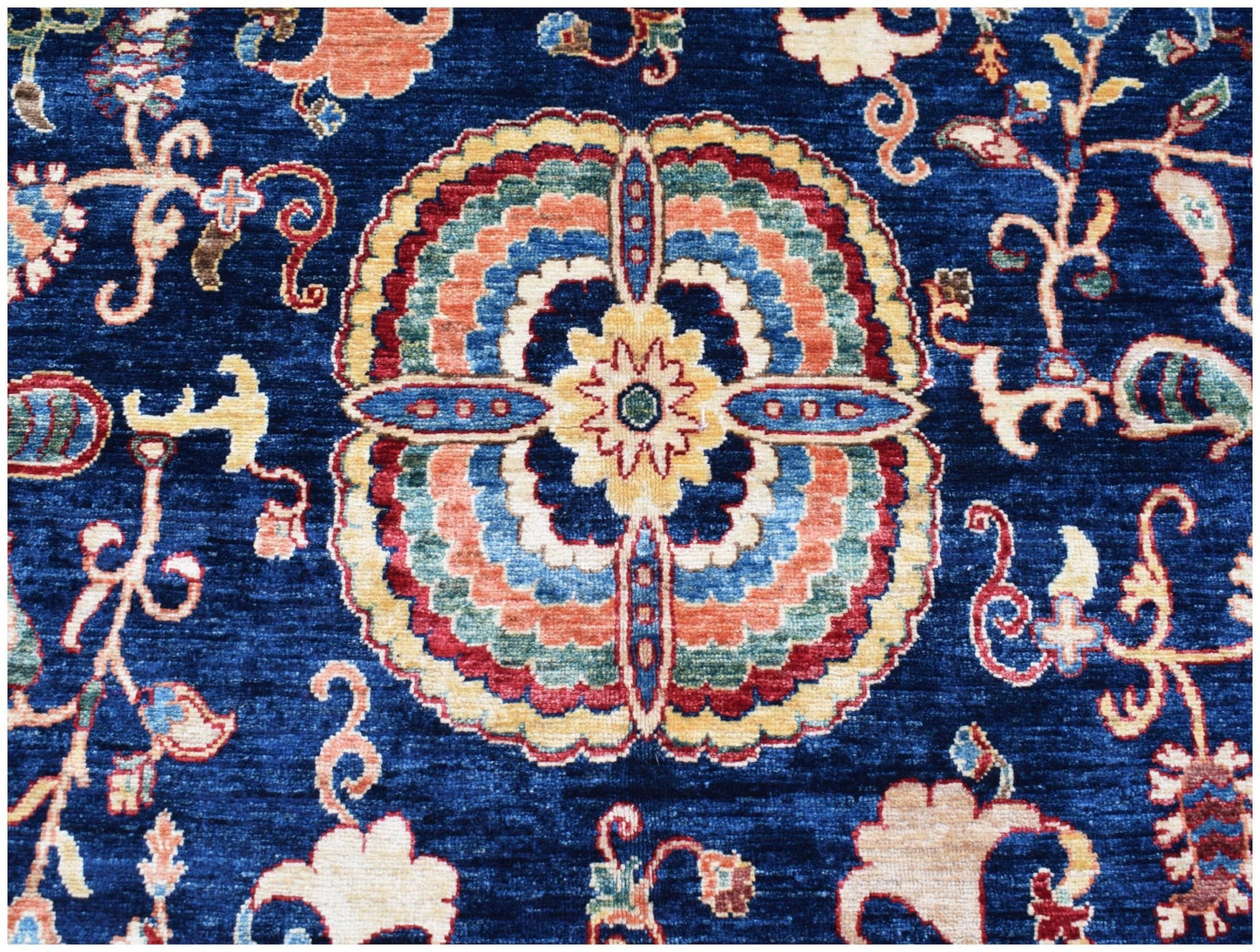 A handmade Afghan Chobi rug featuring a central floral medallion on a deep blue background.