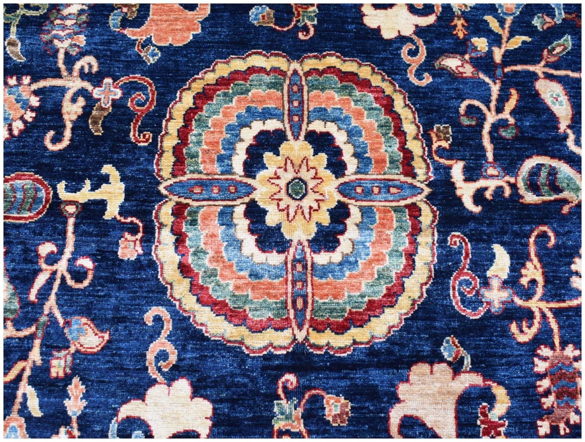 A handmade Afghan Chobi rug featuring a central floral medallion on a deep blue background.