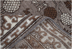 A close-up view of a handmade Afghan Chobi runner featuring a brown and cream geometric pattern.
