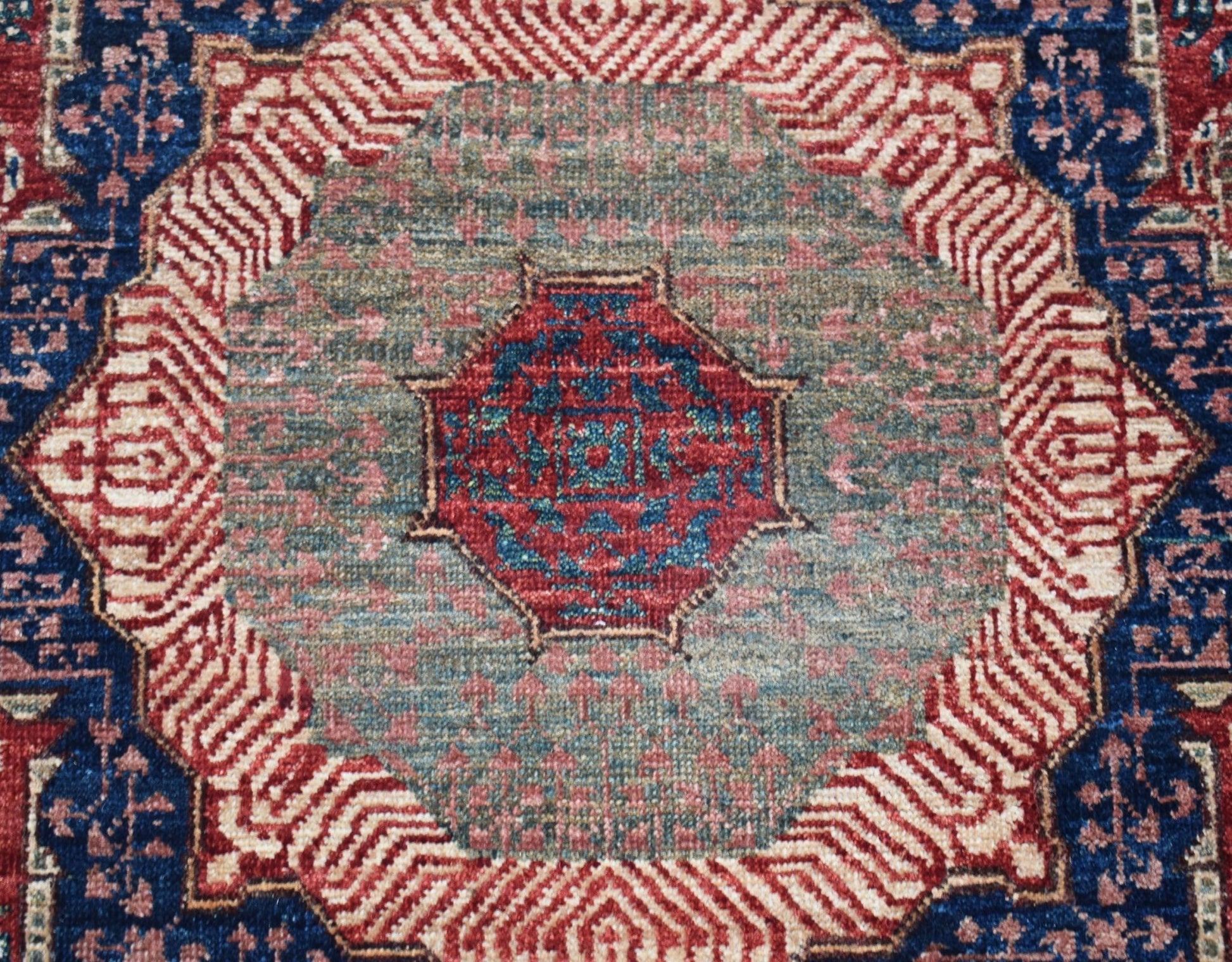 A handwoven Afghan Chobi runner featuring a detailed red and blue Mamluk medallion on a green field.