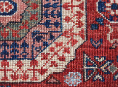 A close-up view of a handwoven Afghan Chobi runner featuring intricate red, blue, and cream patterns.