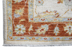 A handmade Afghan Chobi runner featuring a traditional floral pattern in rust and cream tones.