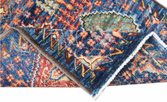 A folded Afghan Chobi runner featuring a traditional intricate pattern in blue, red, and gold.