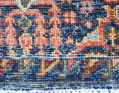 A close-up of an Afghan Chobi runner featuring intricate traditional patterns in blue and red wool.