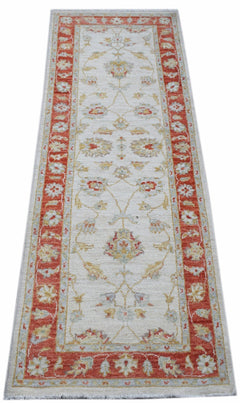A handmade Afghan Chobi runner rug featuring a traditional floral pattern in red and cream tones.