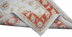 An Afghan Chobi runner with a cream field and a floral red border, shown folded to reveal its back.